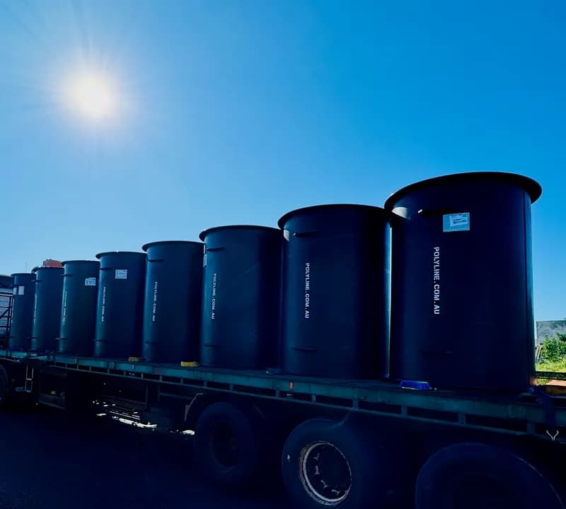 Row of large-diameter HDPE Polyduct sections strapped on a flatbed at sunrise