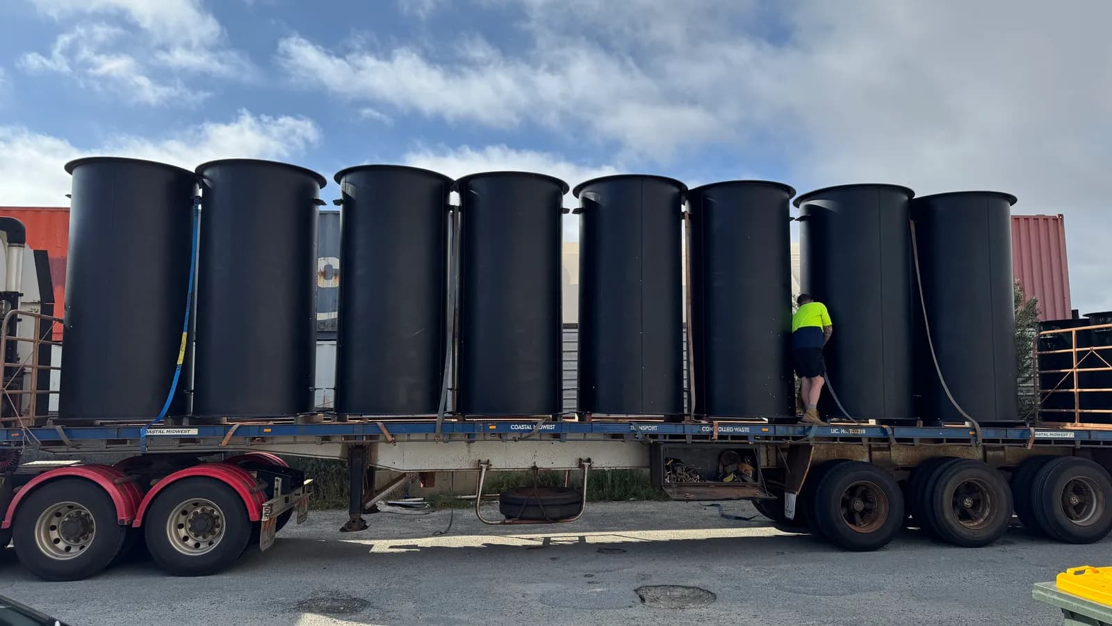 Eight finished HDPE duct sections on a trailer while a worker secures the load