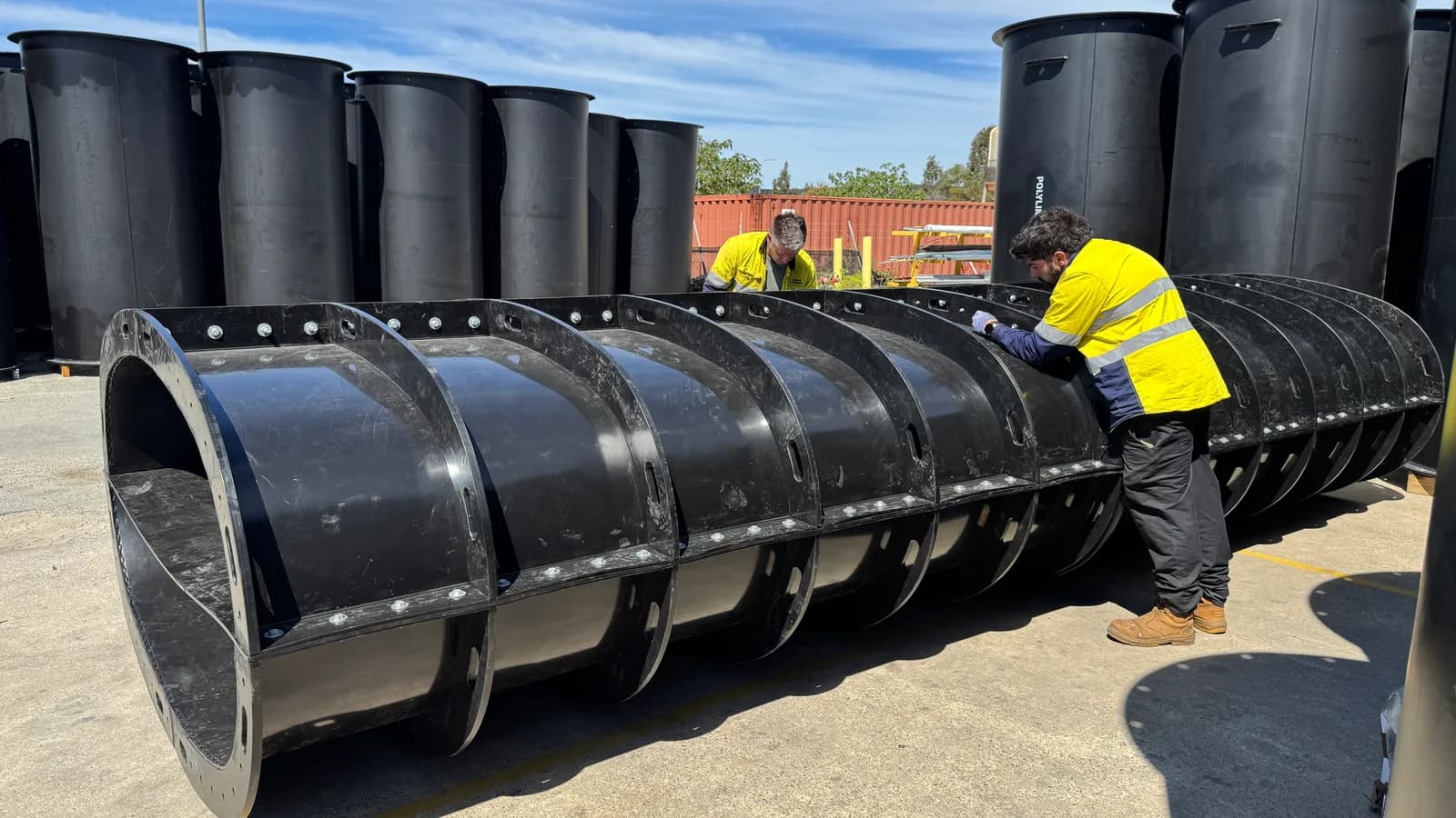Two fabricators bolting the flanges of a split Polyduct section together
