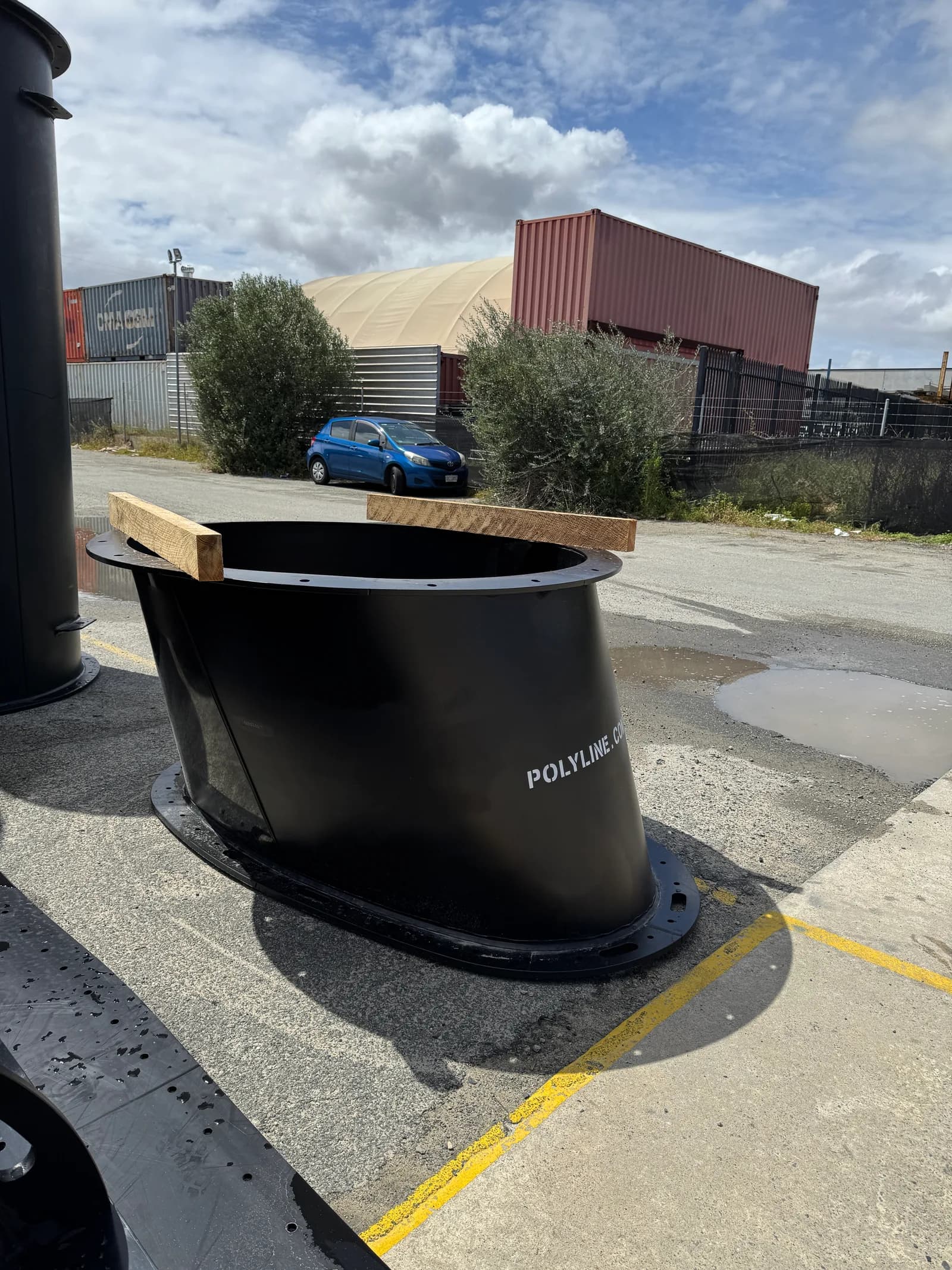 Low-profile oval duct section with flanged ends, sitting in the yard